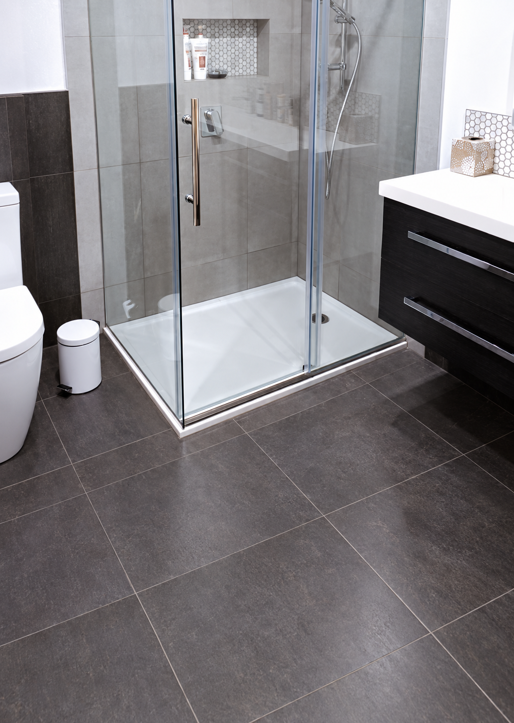 Glass shower enclosure with white shower tray in a tiled bathroom